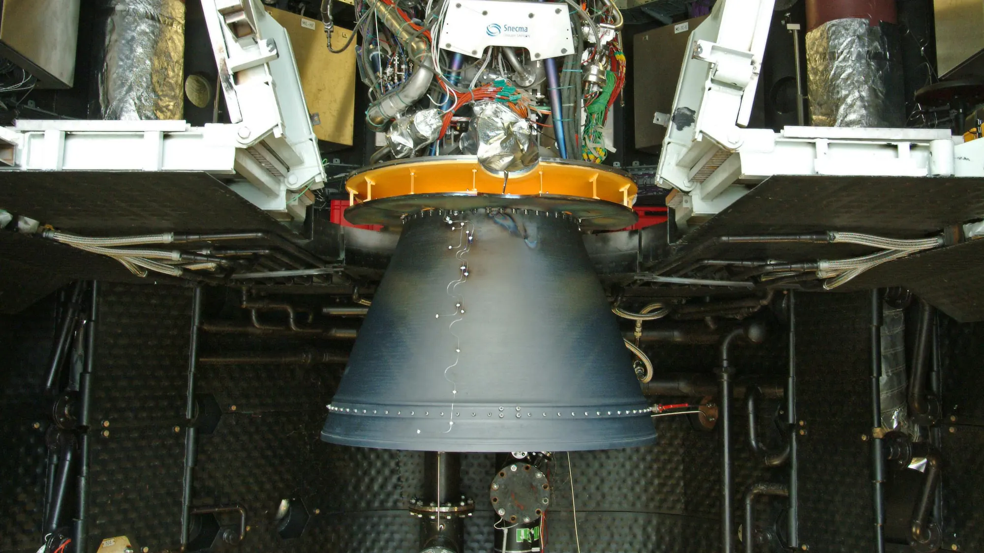 The Vinci upper-stage engine mounted in an altitude test stand: its dark nozzle hangs below a tangle of pipes and cables.