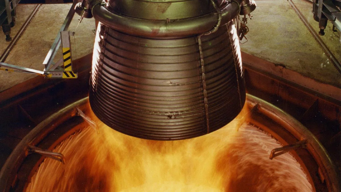 Ein Vulcain-2-Raketentriebwerk auf einem Prüfstand: Flammen schlagen unter der gerippten Metalldüse hervor.
