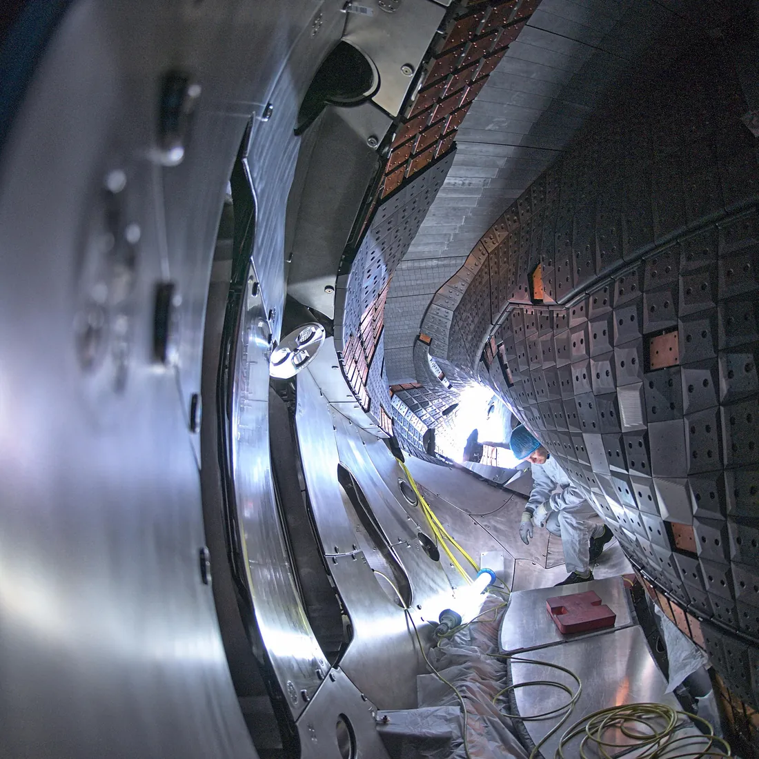 Im Inneren des Fusionsexperiments Wendelstein 7-X: Reihen von Kohlenstoff-Wandkacheln werden montiert.