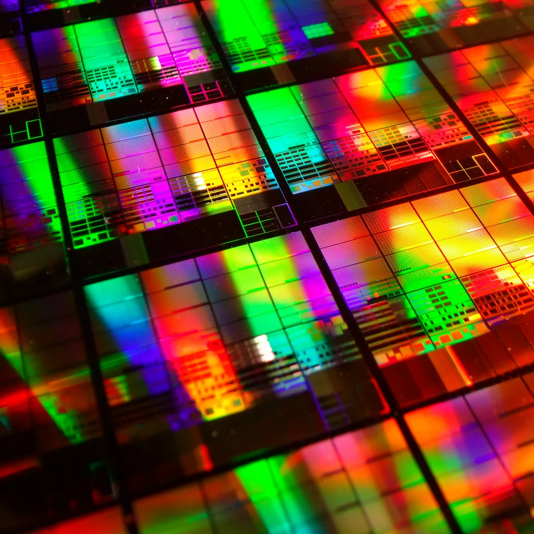 Ein Silizium-Wafer, bedeckt mit Reihen von Chips, so beleuchtet, dass er farbig schimmert.