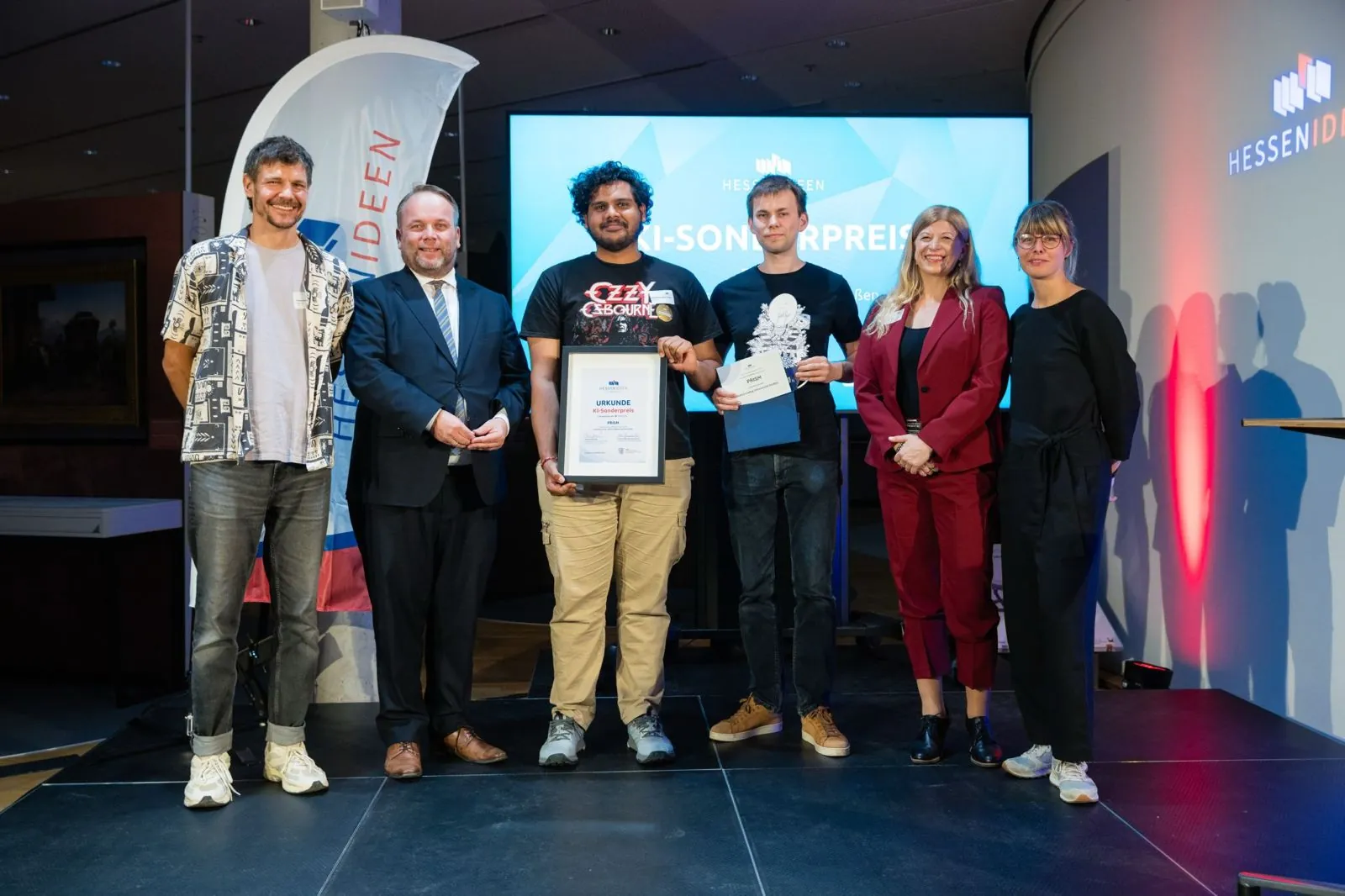 Team PRISM on stage at the Hessen Ideen awards, holding the KI-Sonderpreis certificate, with the organisers.